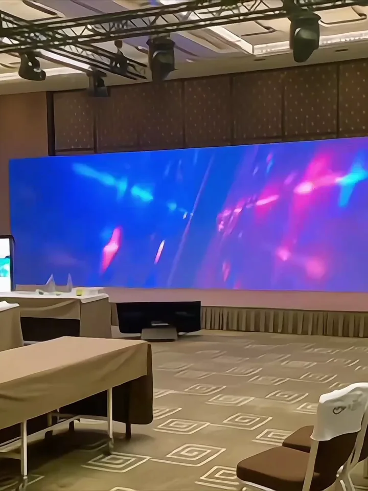 LED wall lit in a conference room, tables laid for the session