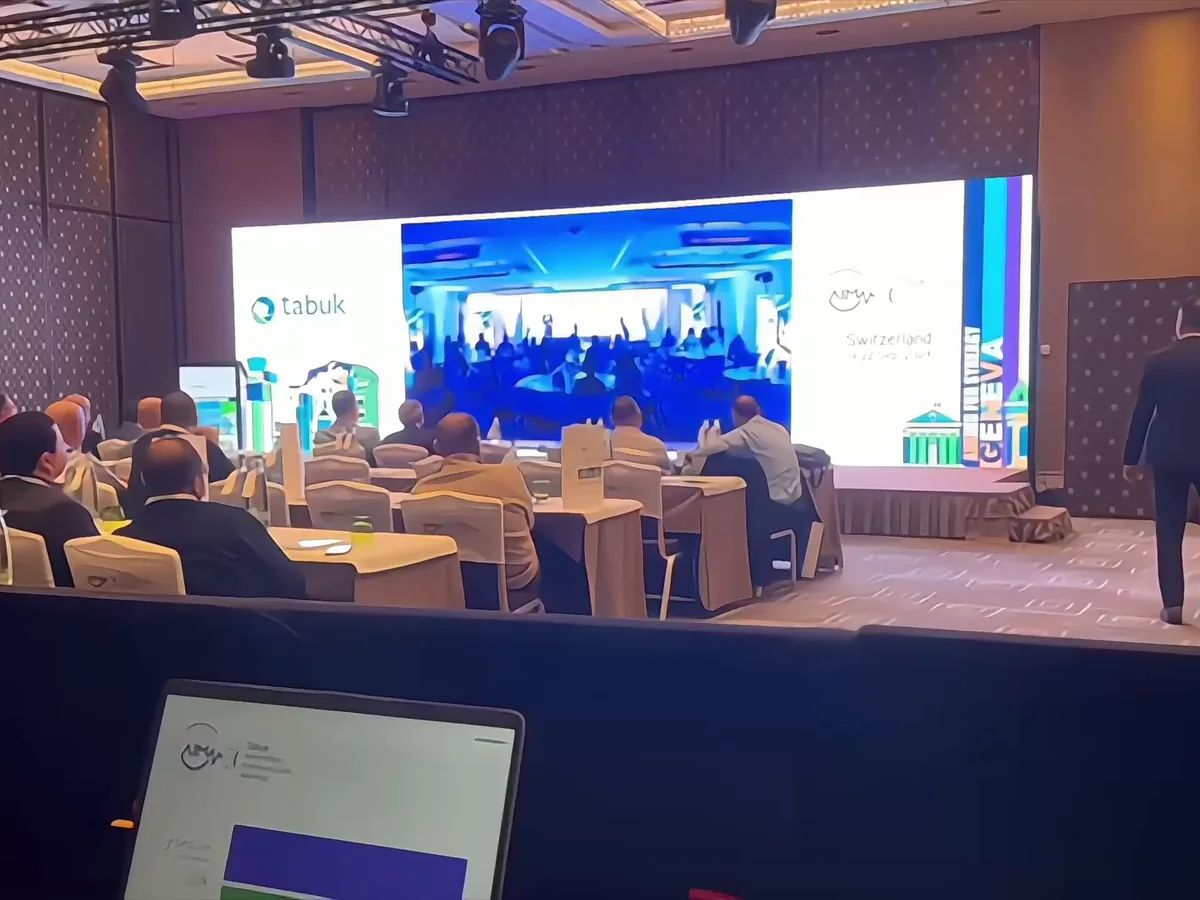 LED wall across the back of a conference stage, the audience seated at tables