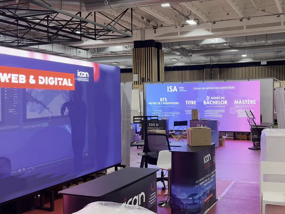 Two LED walls on school stands in an exhibition hall, course titles on the far screen