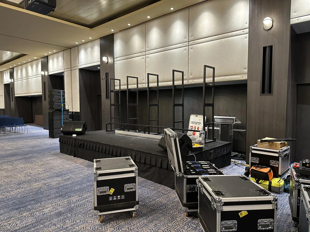 Steel ladder frames standing on a stage in a hotel function room, open flight cases of LED panels in front