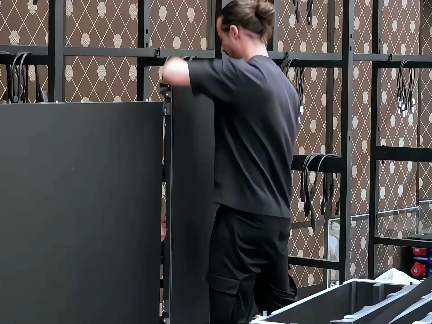 A technician fitting an LED panel onto the steel frame of a wall in a function room