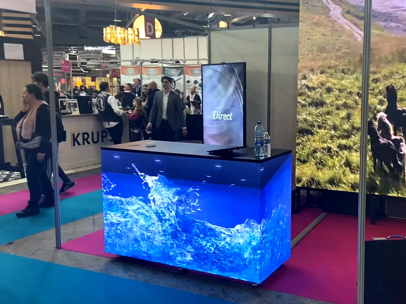 Comptoir LED affichant une scène aquatique sur ses faces, à côté d’un écran géant LED dans un hall d’exposition