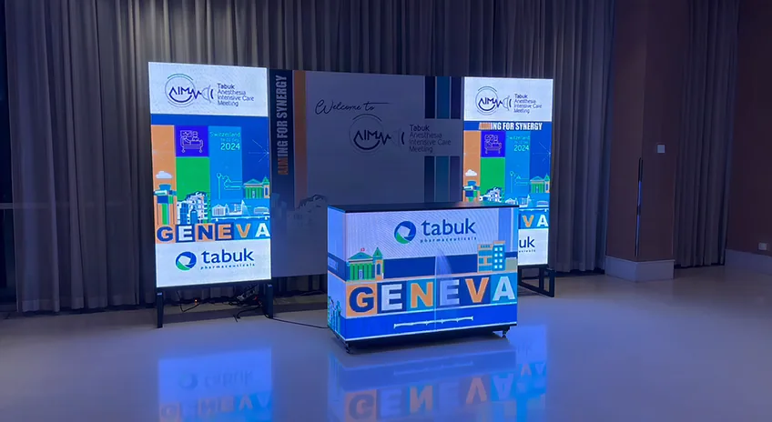 Banque d’accueil LED à la façade entièrement allumée, entre deux totems LED verticaux, dans une salle d’événement