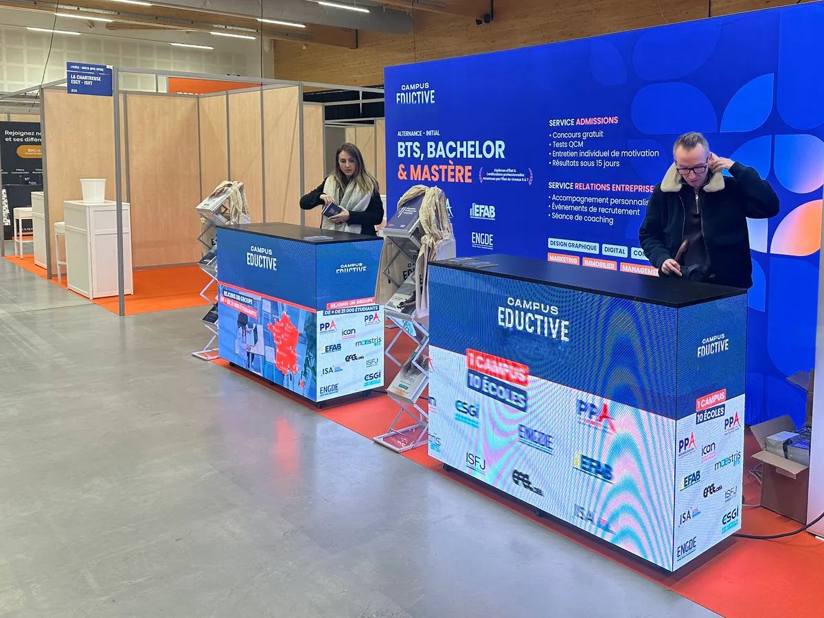 Two LED counters with pictures on every face, on a stand at a trade fair