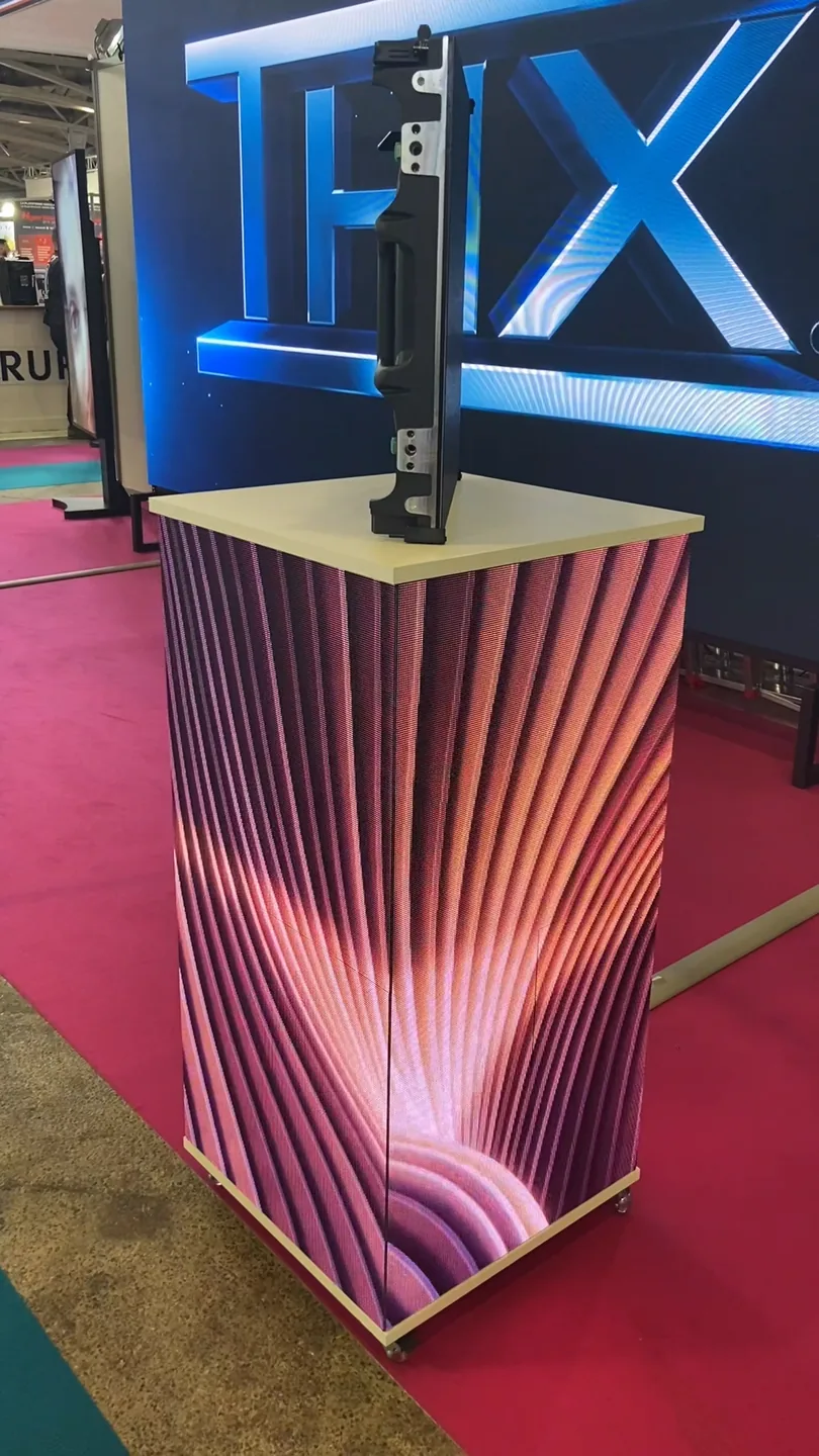 Mange-debout LED sur un stand de salon, un motif de vagues roses courant sur deux de ses faces