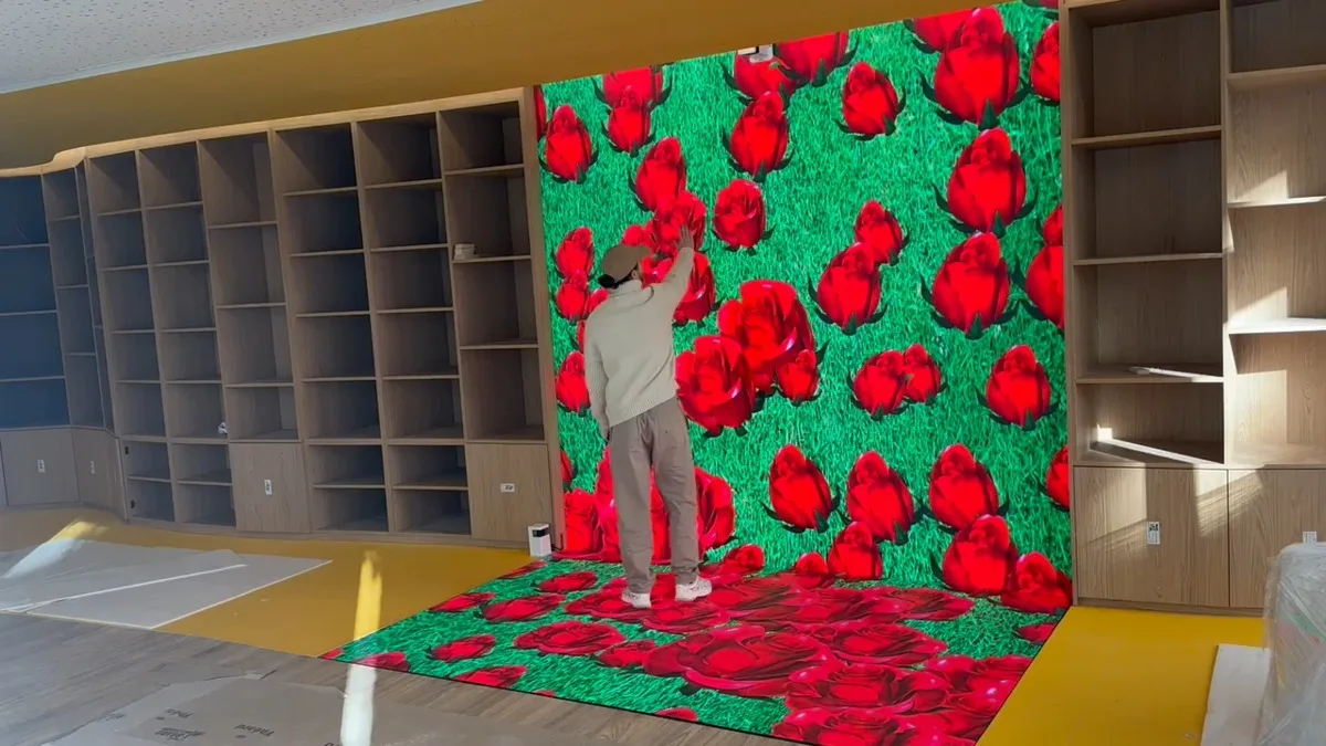 Interactive LED wall and floor lit with red roses in a shop being fitted out, a man touching the wall