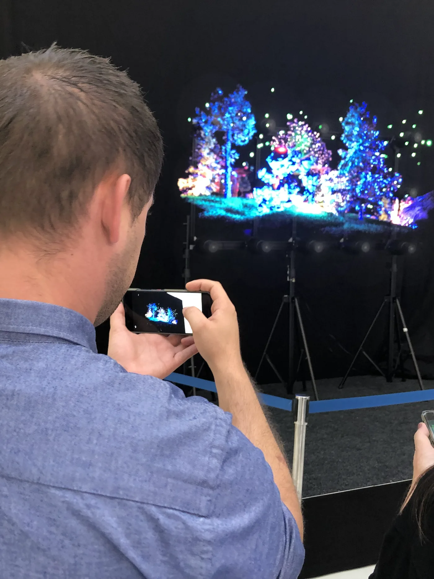 A visitor filming HYPERVSN holograms: a forest floating in mid-air