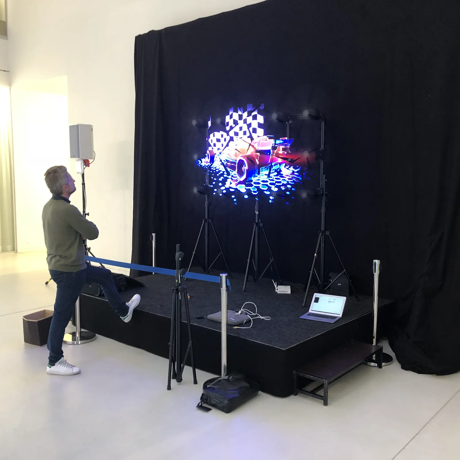 HYPERVSN holographic displays on a black stage, a visitor watching the floating picture