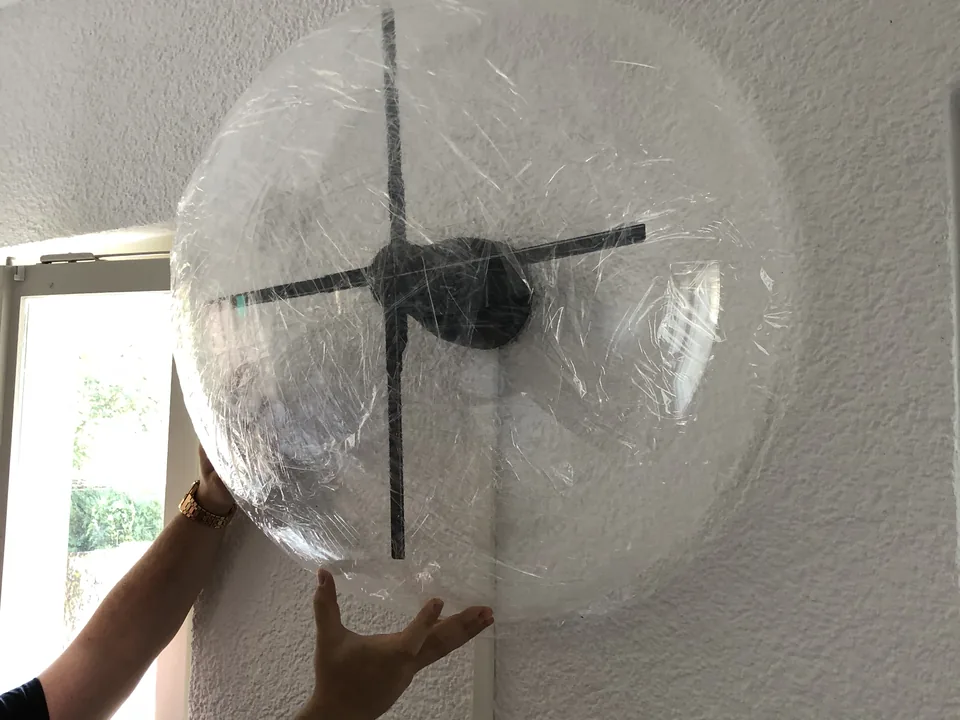 Un capot de protection transparent, en forme de dôme, posé sur un ventilateur HYPERVSN fixé au mur