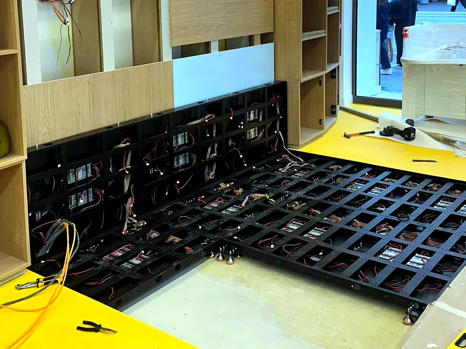Panels of an interactive LED floor being assembled on site, cabling visible before the covers go on
