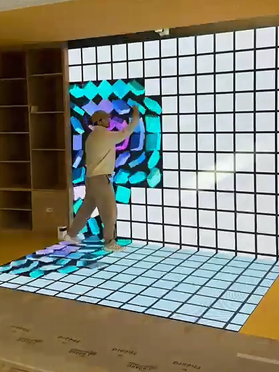 Visitor walking on an interactive LED floor and touching the LED wall, the picture answering the steps and the hand