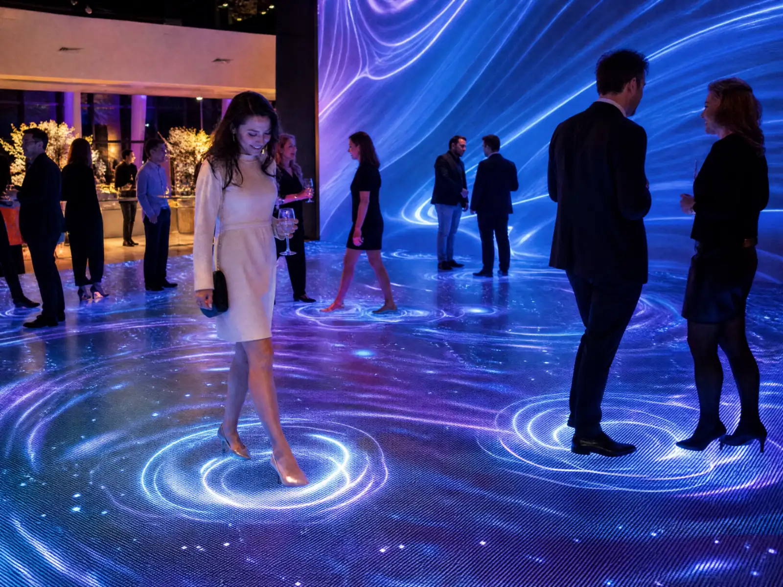 Guests at an evening event walking on an interactive LED floor, rings of light spreading under their steps