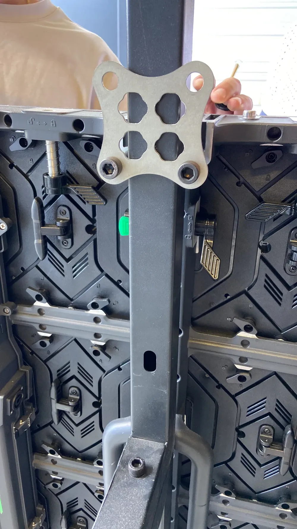 A hand holding a metal fixing plate against the back of LED panels, where their corners meet