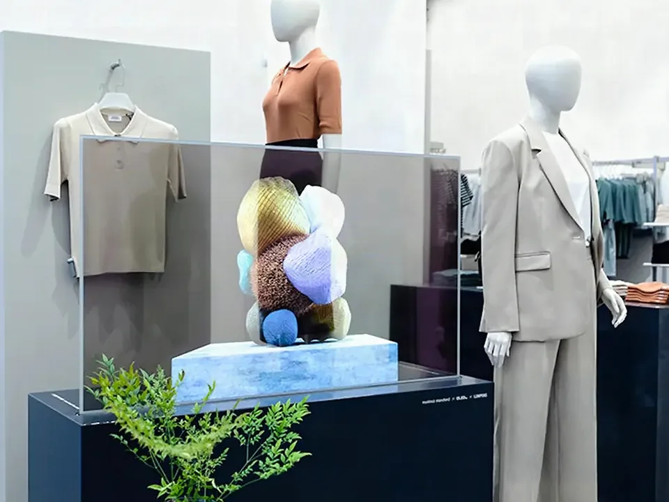 Transparent display case between mannequins in a fashion store, a colourful sculpture inside the glass