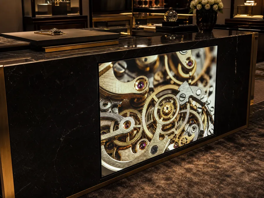 Black marble counter in a luxury store, a screen set into its front showing watch gears