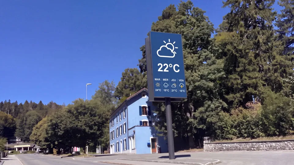 Outdoor LED screen on a mast beside a road, the weather on screen in full daylight