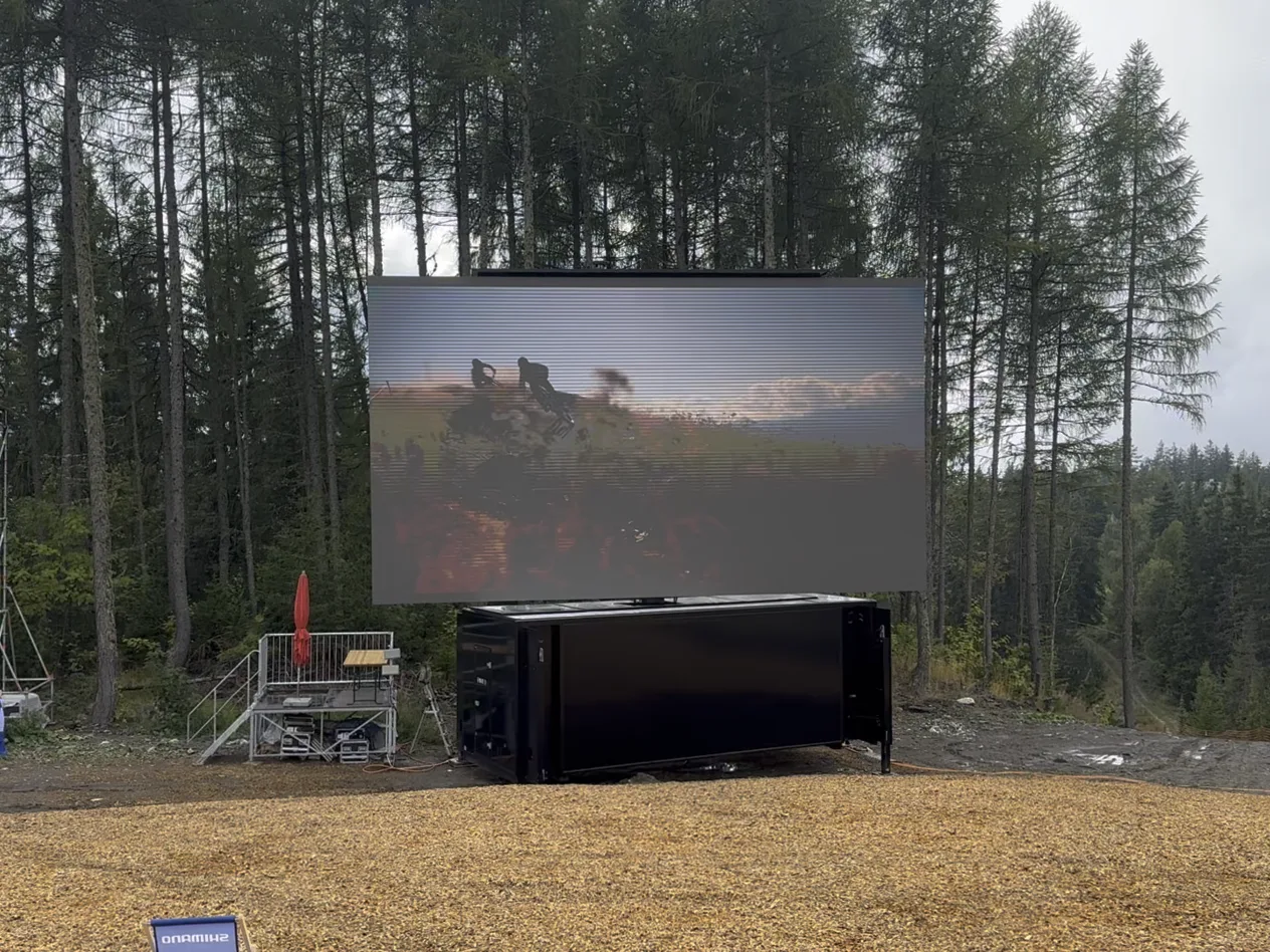 Outdoor LED screen set up in a forest clearing for an outdoor event