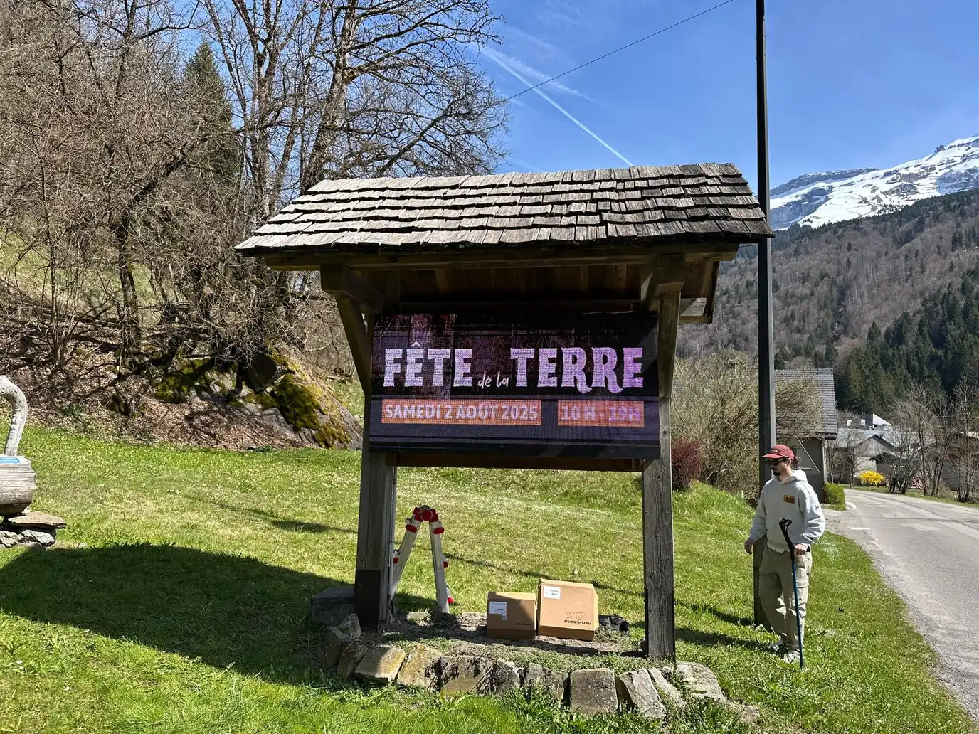 Outdoor LED screen built into the noticeboard of an alpine village, under its shingle roof