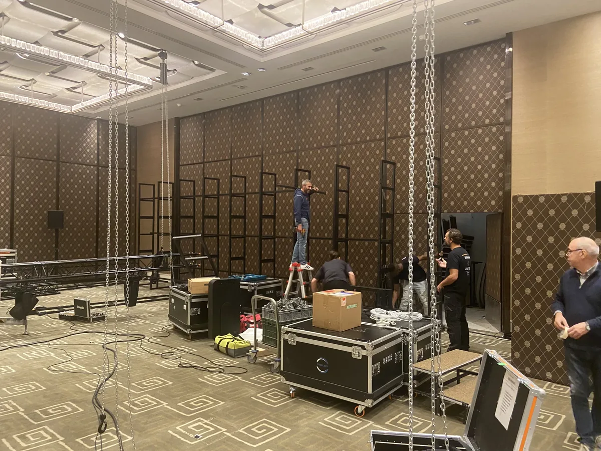Function room during set-up, truss hanging from chains, flight cases and a crew at work