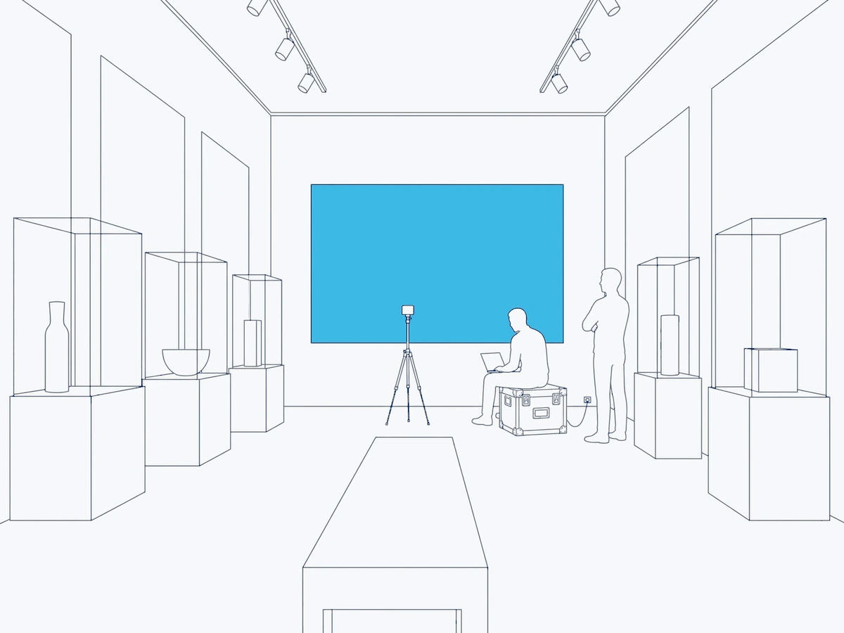 Line illustration: a showroom in the evening, the display lit on the back wall, a technician on a flight case with a laptop and a colour probe on a tripod