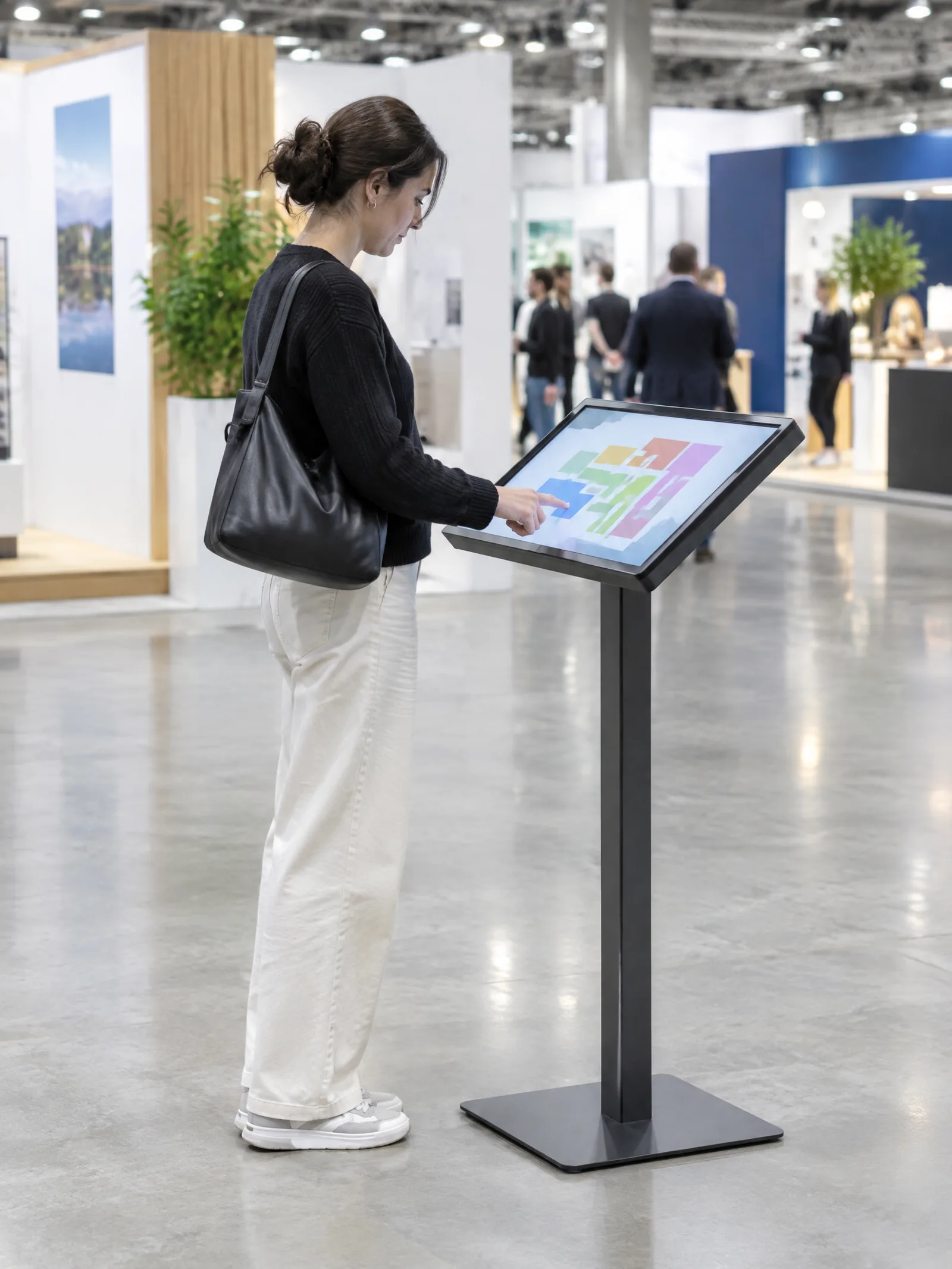 Visitor using a touchscreen kiosk tilted on a stand, a floor plan on screen