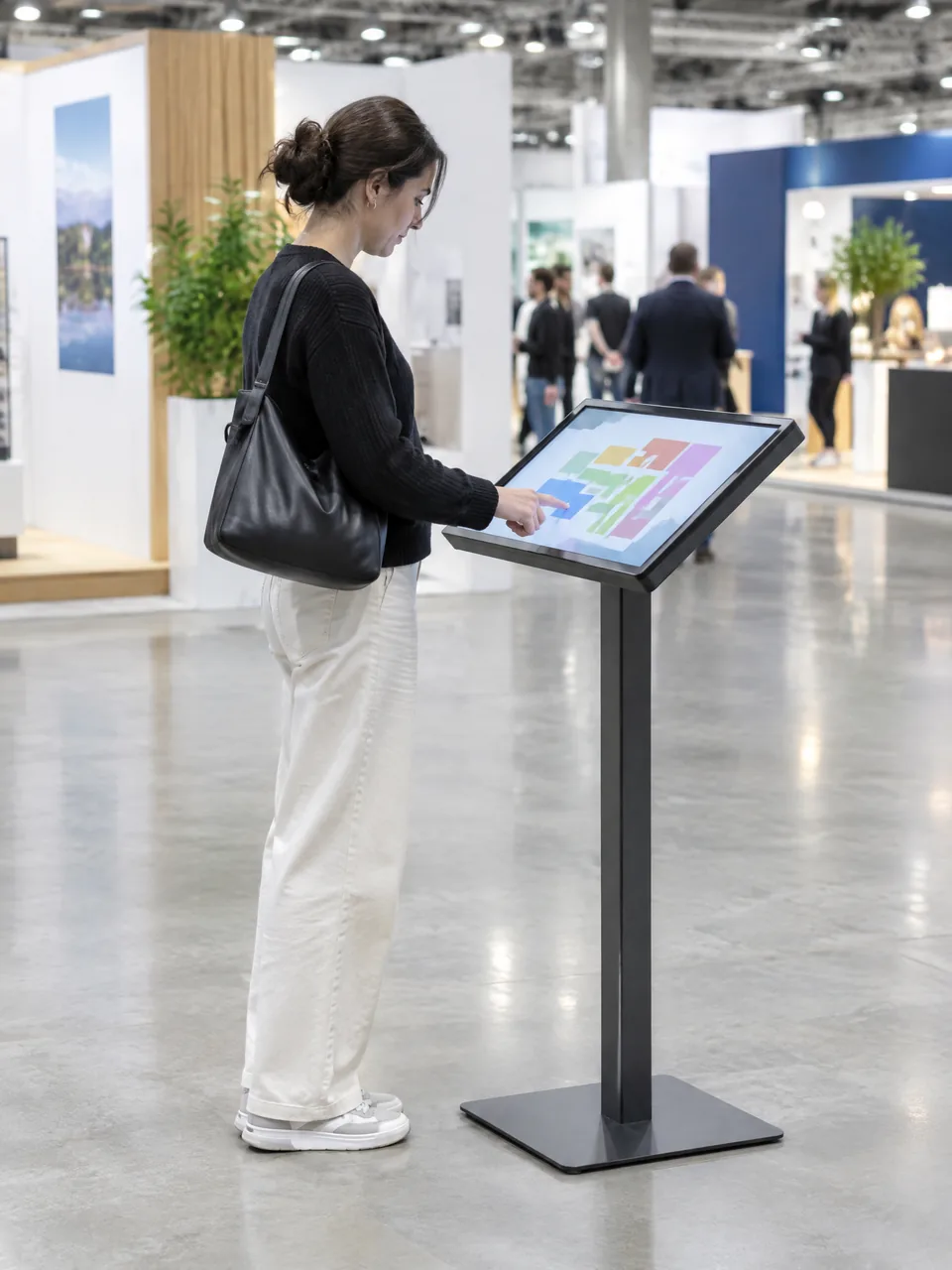 Visitor using a tilted touch screen on a stand at a trade show